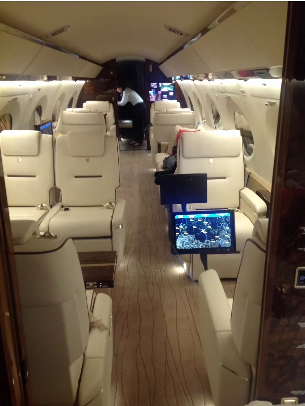 Cabin of a large business jet with cream leather seats and a moving-map display